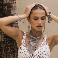 Woman wearing silver jewelry and a sequin top against a neutral background