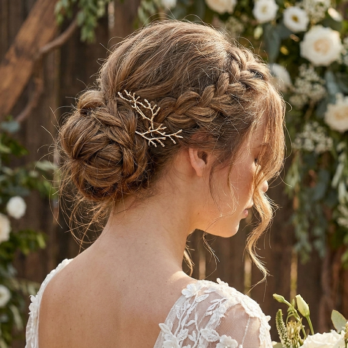 A woman in a white lace wedding dress shown from the back, wearing a delicate gold hair accessory shaped like small branches or leaves tucked into her braided updo. Arbors Hair Pin Set - The Songbird Collection