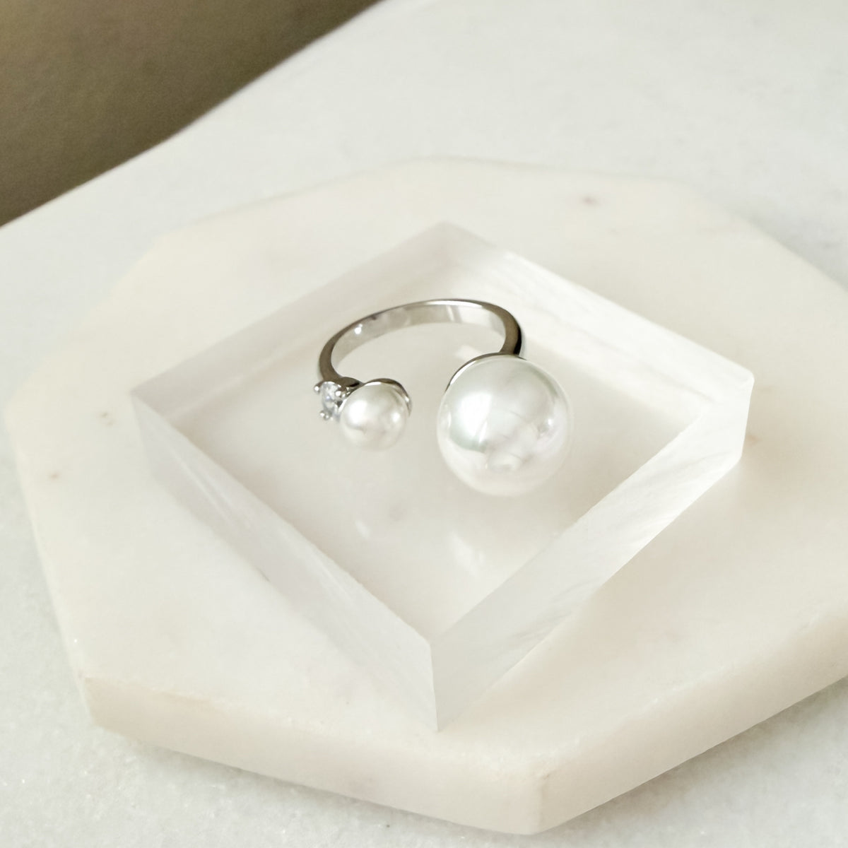 Silver ring with a pearl on a white marble surface  Arista Open Pearl Ring - stainless steel - The Songbird Collection
