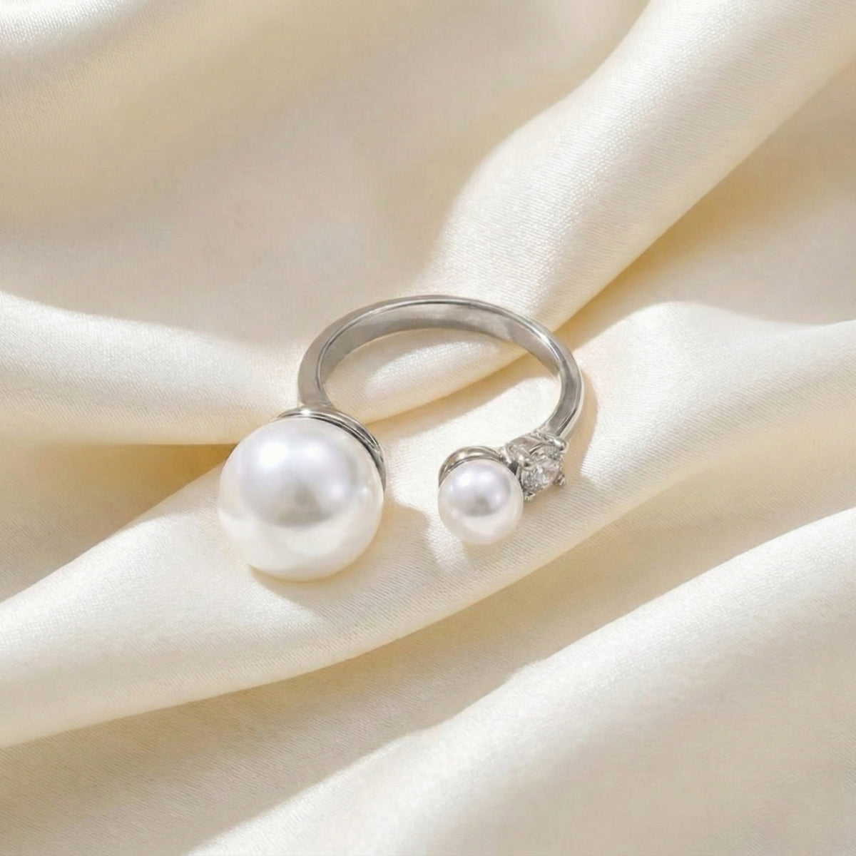 Silver ring with pearls on a soft beige fabric background  Arista Open Pearl Ring - stainless steel - The Songbird Collection