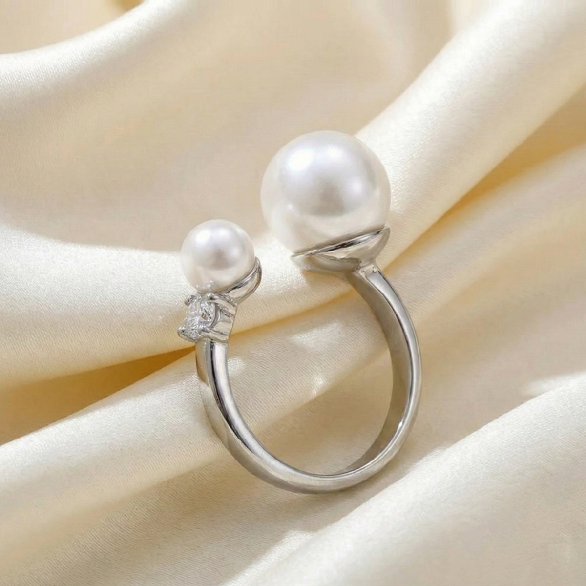 Silver ring with pearls on a soft beige fabric background  Arista Open Pearl Ring - stainless steel - The Songbird Collection
