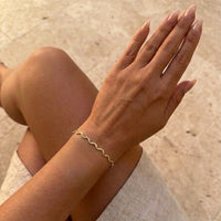 Gold bracelet on a wrist with a blurred background