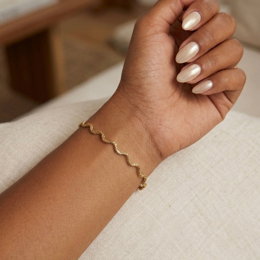 Gold bracelet on a wrist with a blurred background