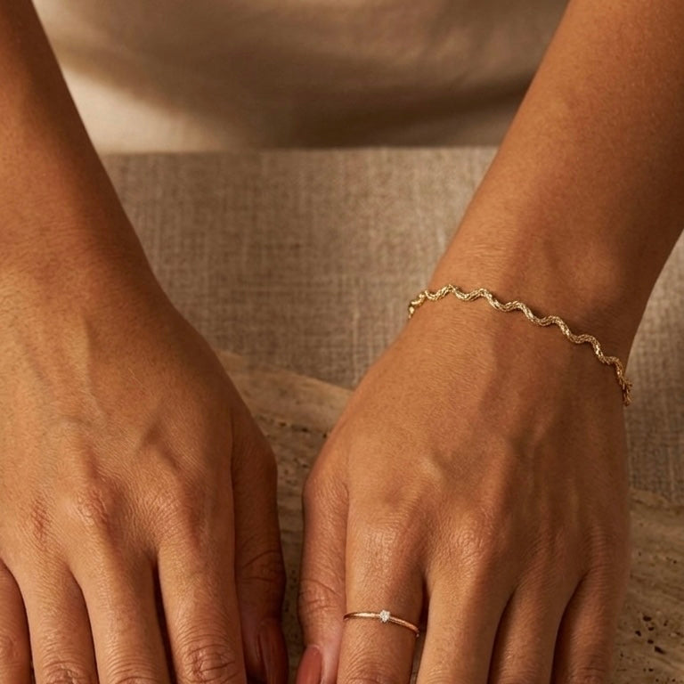 Close-up of two hands with gold bracelets on a textured surface