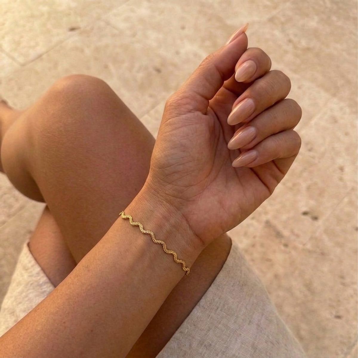 Gold bracelet on a wrist with a blurred background