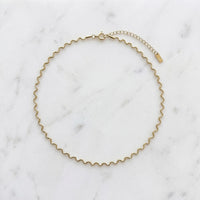 Gold wavy chain necklace on a marble surface - Aura Ripple Chain Necklace - The Songbird Collection