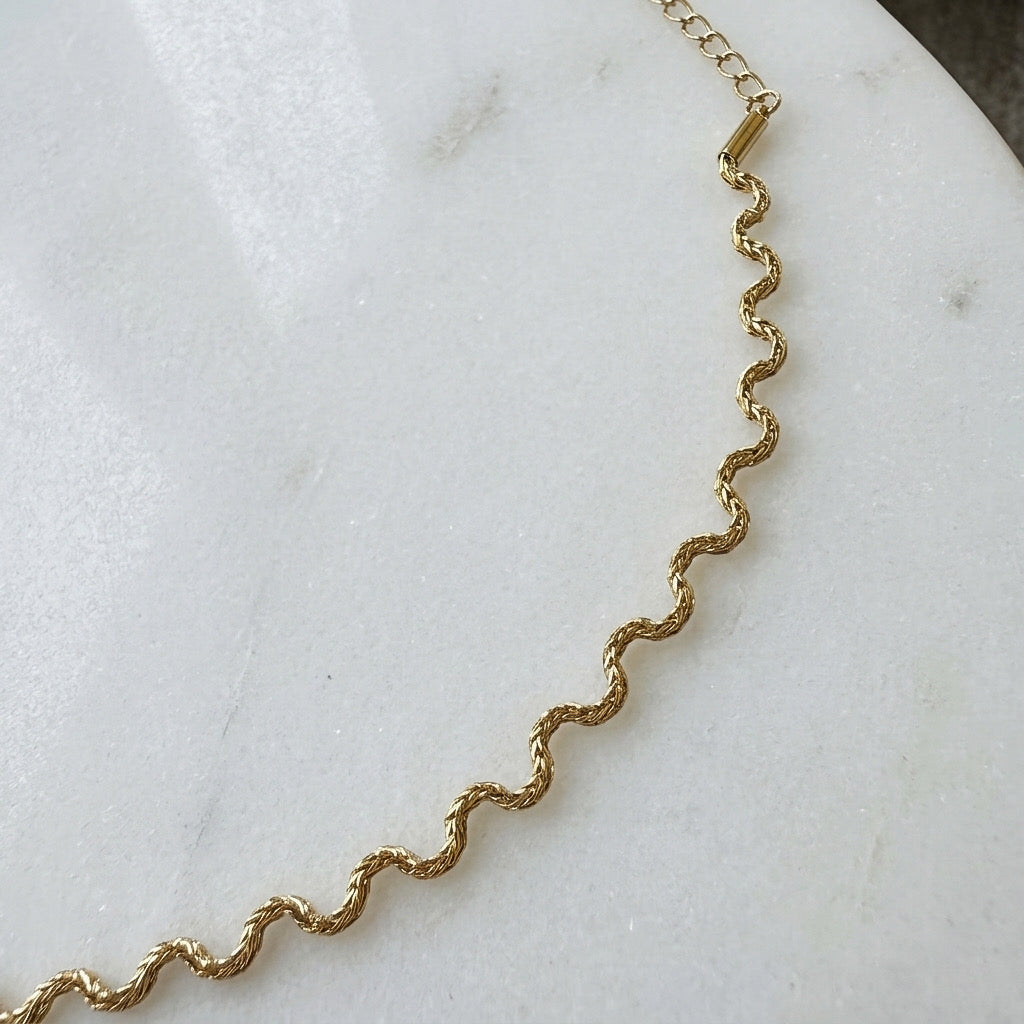 Gold  wavy chain  necklace on a marble surface - Aura Ripple Chain Necklace - The Songbird Collection