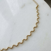 Gold  wavy chain  necklace on a marble surface - Aura Ripple Chain Necklace - The Songbird Collection