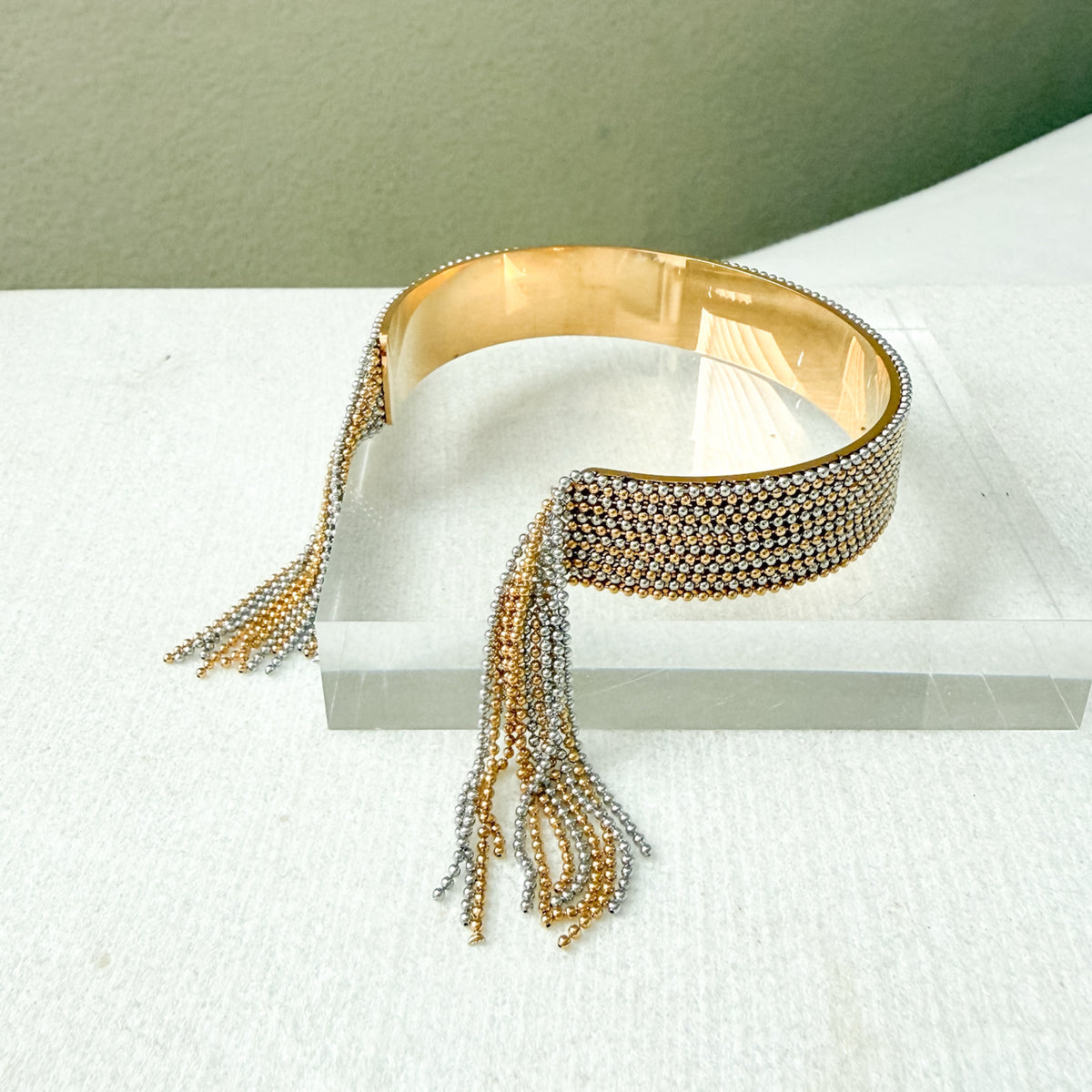 Gold and silver beaded bracelet cuff  with tassels on a white surface