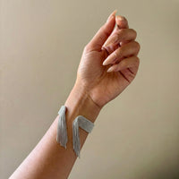 Hand wearing a delicate bracelet against a neutral background - Beaded_Fringe_Statement_Bracelet_Cuff_-_The_Songbird_Collection