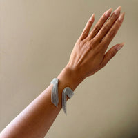 Hand wearing a silver bracelet on a beige background - Beaded_Fringe_Statement_Bracelet_Cuff_-_The_Songbird_Collection