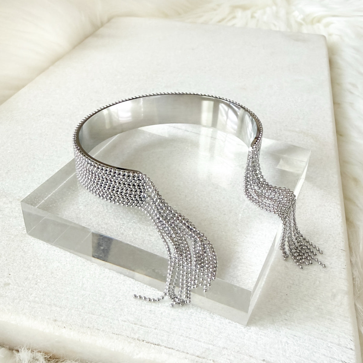 Silver beaded cuff  on a clear stand with a soft white background