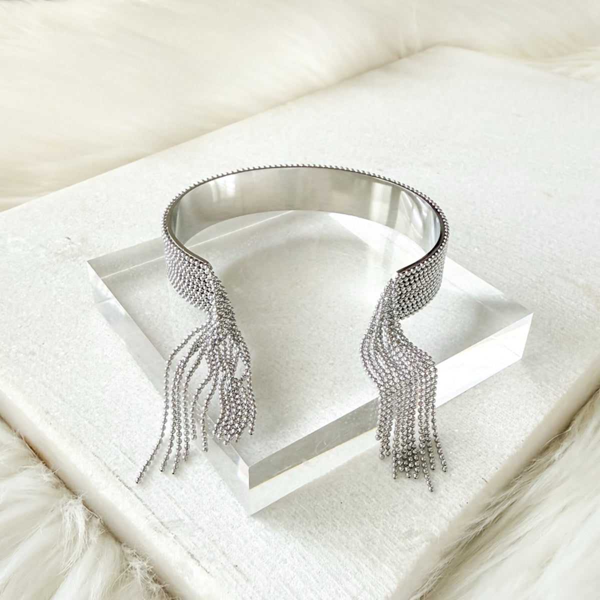 Silver fringe bracelet cuff on a white surface