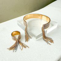 Gold and silver beaded bracelet cuff and ring on a white surface with a neutral background