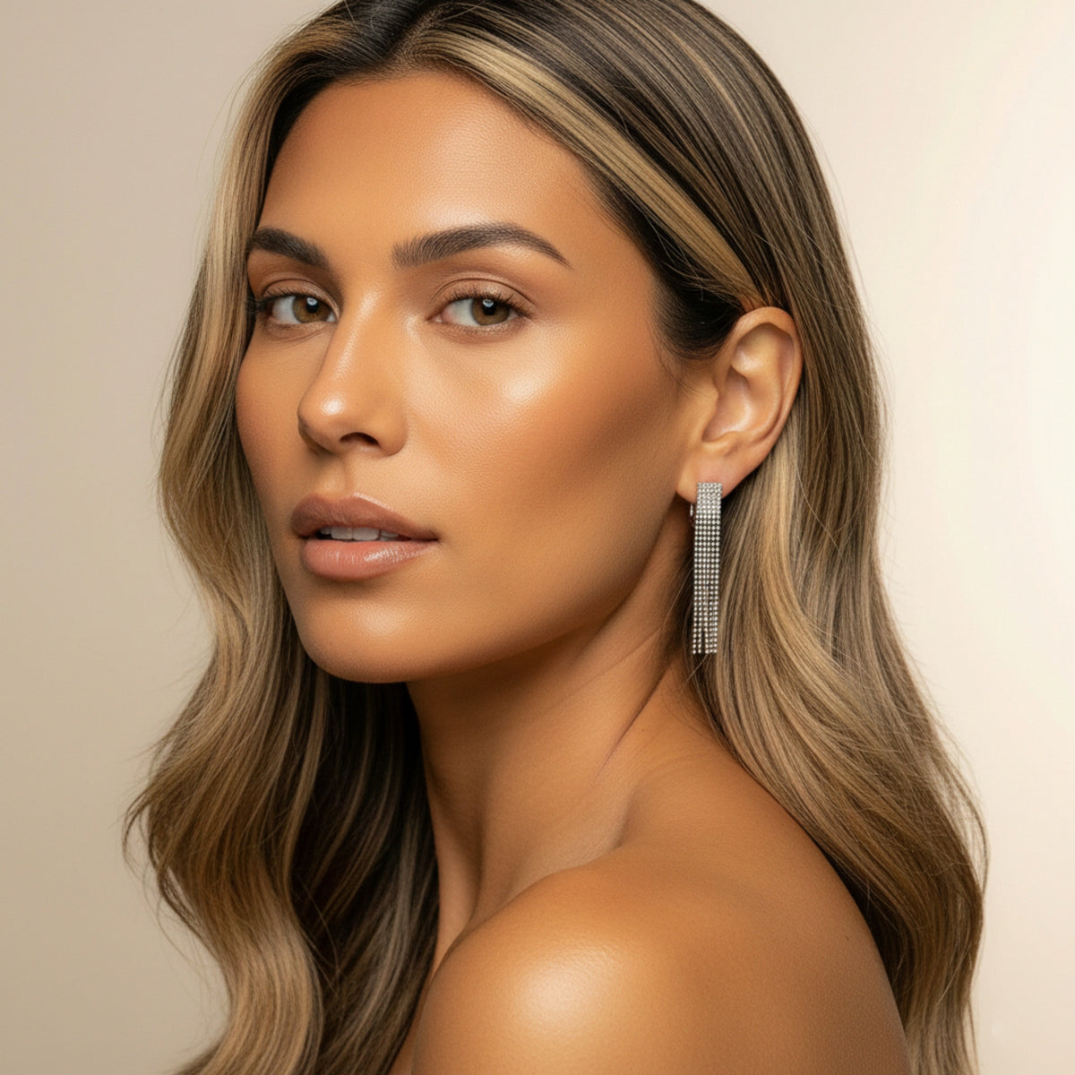 Woman with long, wavy hair wearing a silver earring against a beige background - Beaded Fringe Statement Earrings - The Songbird Collection