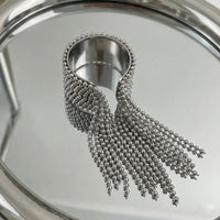 Silver beaded tassel on a reflective surface
