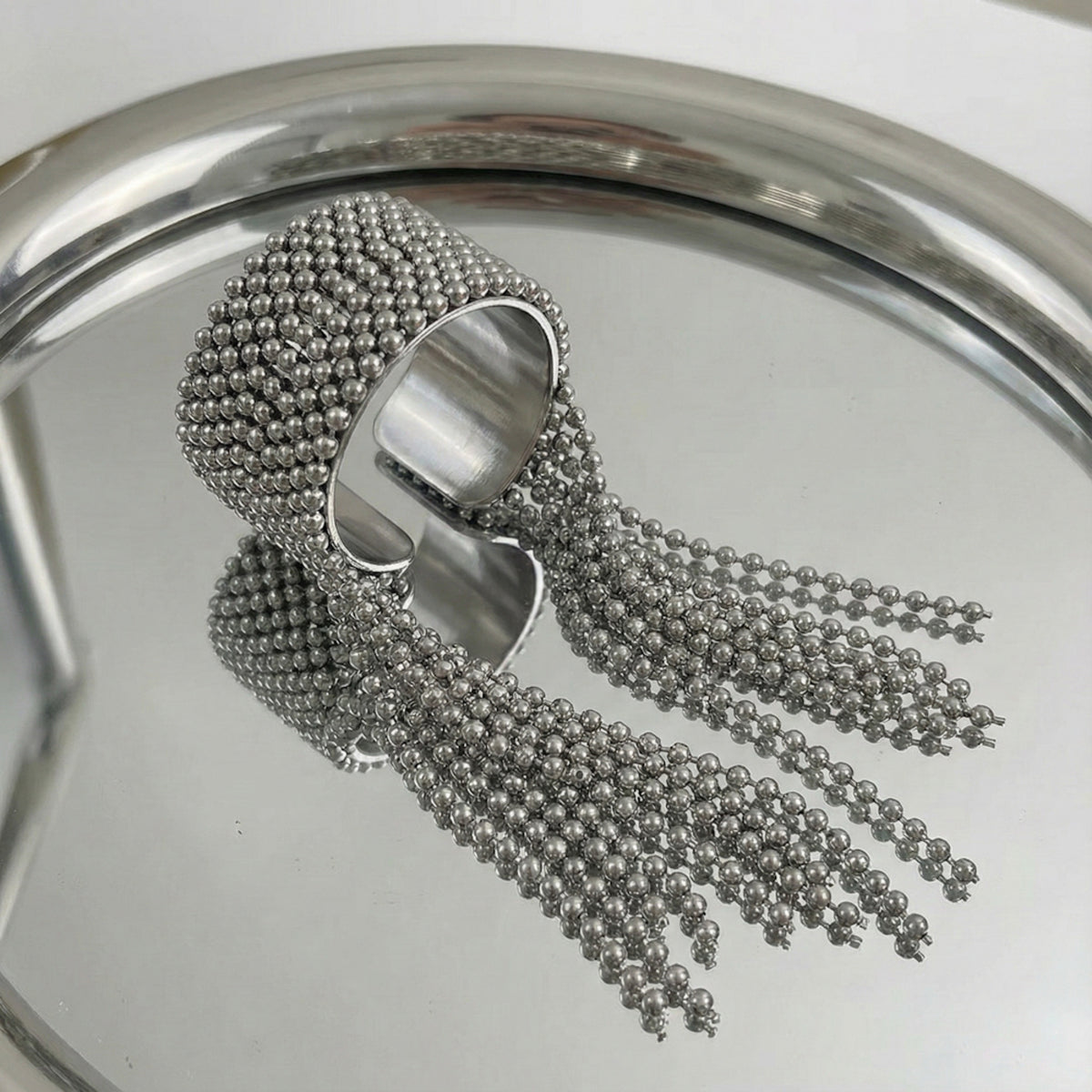 Silver beaded ring on a reflective surface
