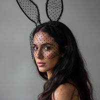 Woman wearing bunny ears with a veil on a gray background