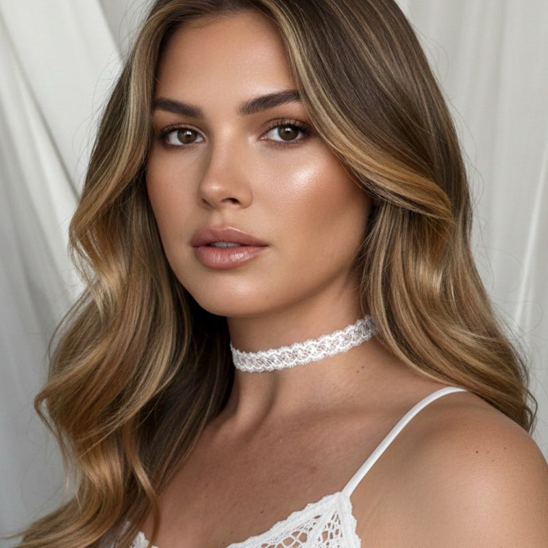 Woman wearing a white lace choker and top against a plain background