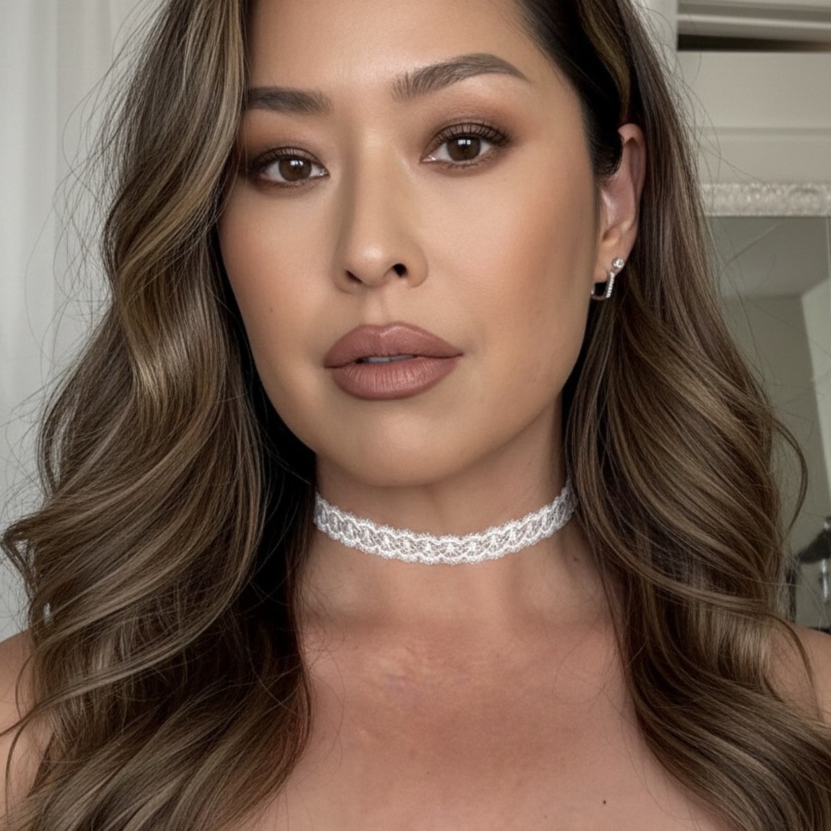 Woman wearing a delicate white choker necklace with a neutral background
