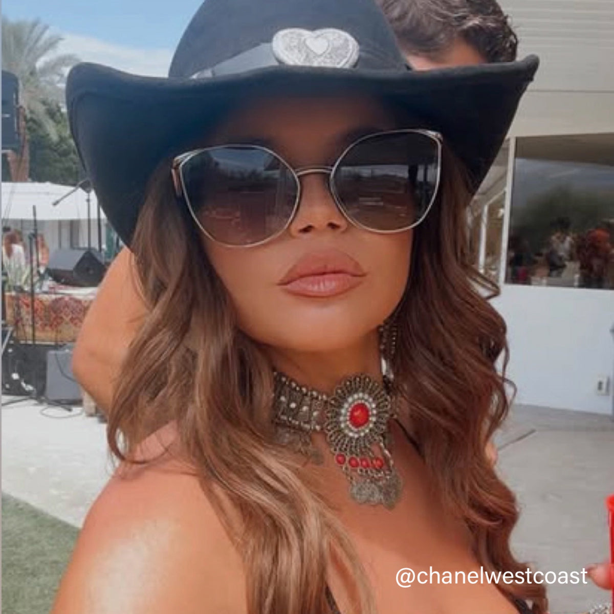 CHanelWestCoast wearing a black hat and sunglasses with a scenic background