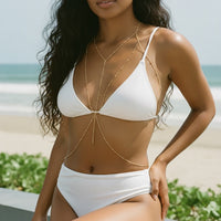 Woman wearing a white bikini with gold accents on a beach