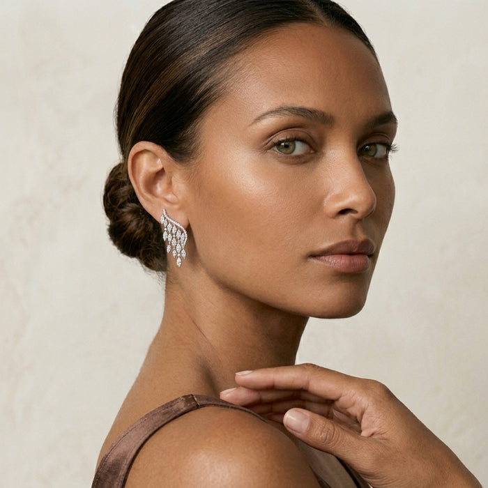 Woman wearing a dangling earring with a neutral background. Chandelier Earrings and Ring - The Songbird Collection