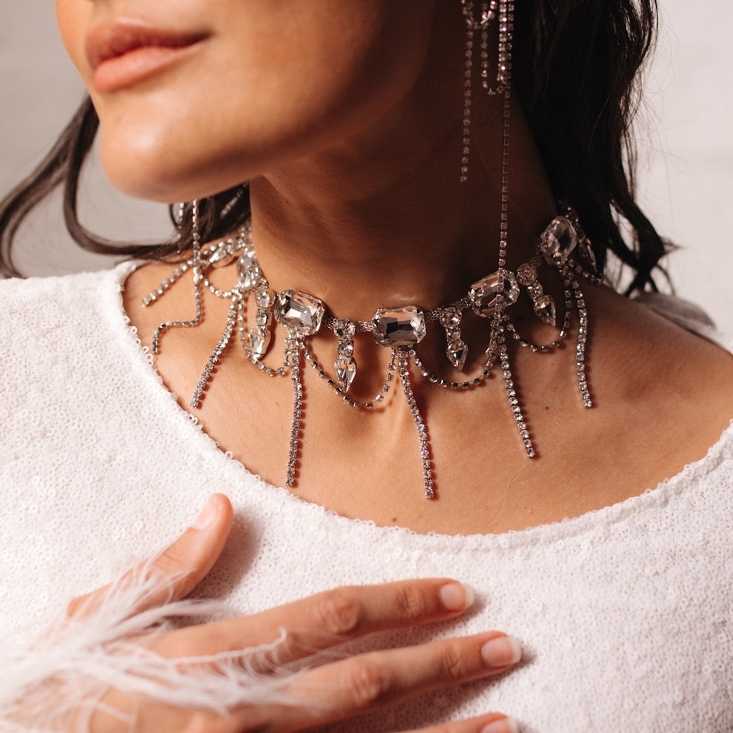 A close-up of a Chunky Geo Rhinestone Drop Necklace with a detailed chain design and rhinestone embellishments, worn by a person.