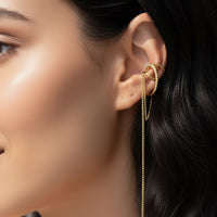 Close-up of a woman's ear wearing a gold earring with a dangling chain.