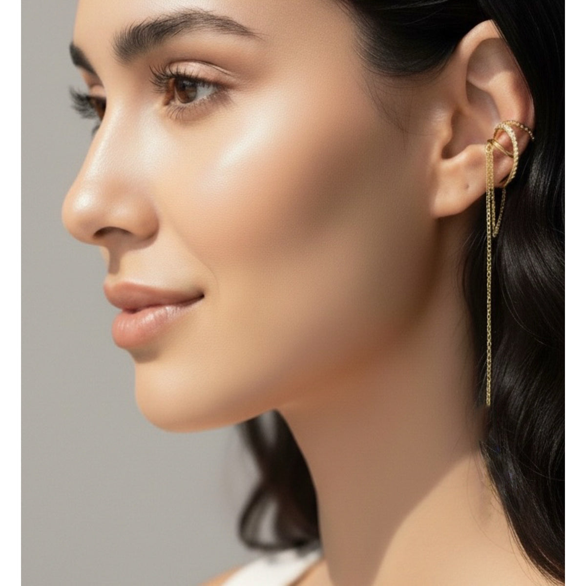 Close-up of a woman wearing gold earrings with a neutral background