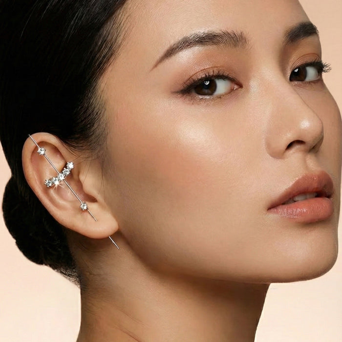 Close-up of a woman wearing a delicate earring/ ear hook/ ear pick/ thread throguh earring on a beige background