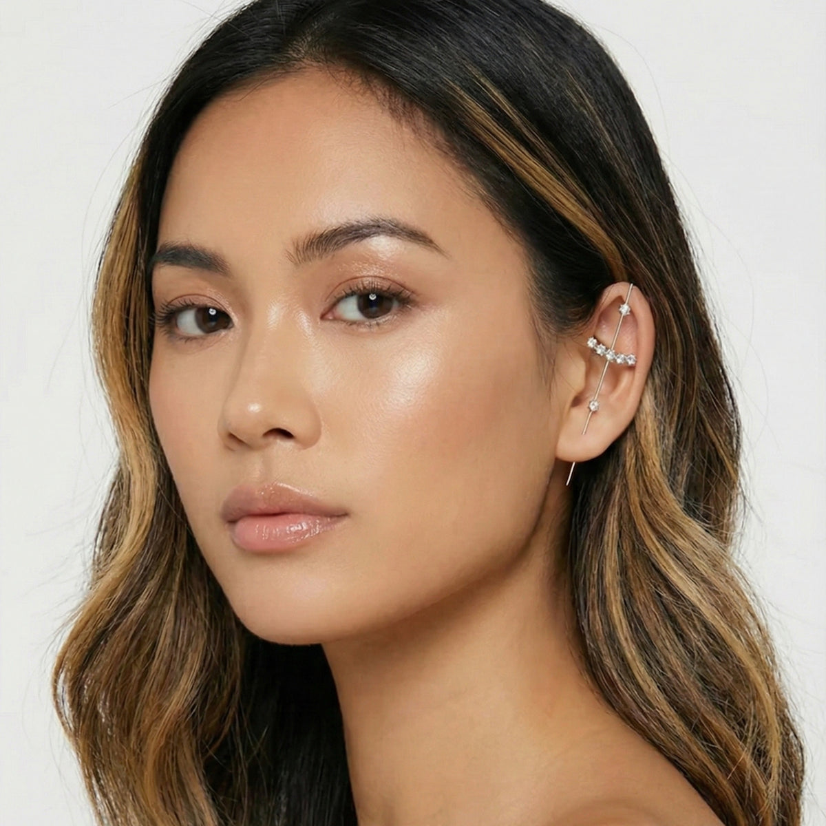 Close-up of a woman with long, wavy hair wearing an earring against a white background  Crystal_Bliss_Ear_Hook_Ear_Cuff-Earrings-The_Songbird_Collection