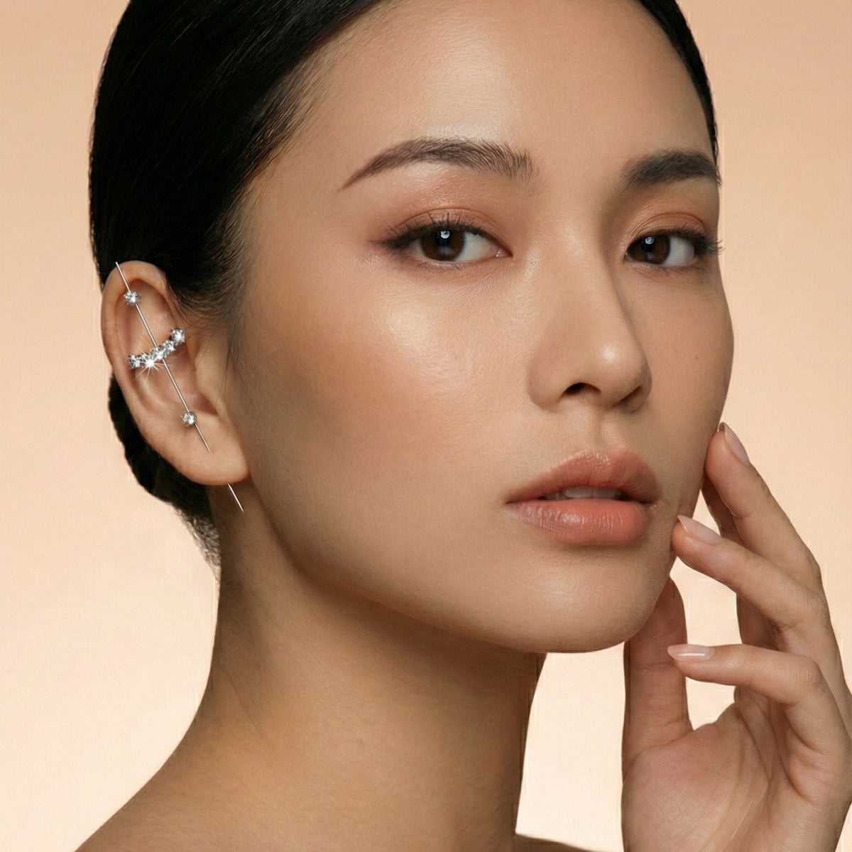 Close-up of a woman's face with a neutral background  Crystal_Bliss_Ear_Hook_Ear_Cuff-Earrings-The_Songbird_Collection