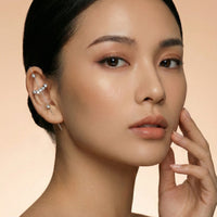 Close-up of a woman's face with a neutral background  Crystal_Bliss_Ear_Hook_Ear_Cuff-Earrings-The_Songbird_Collection