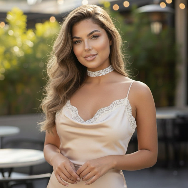Woman wearing a beige lace top outdoors with blurred background