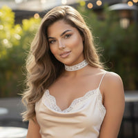 Woman wearing a white lace choker and beige top with lace details outdoors