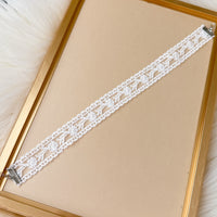 White lace choker  on a gold frame with a beige background