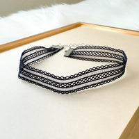 Black lace choker necklace on a white surface