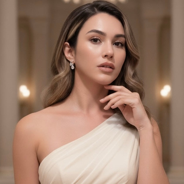 Woman wearing a one-shoulder white dress with a blurred indoor background