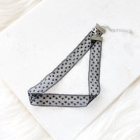 Black polka dot choker necklace on a white background