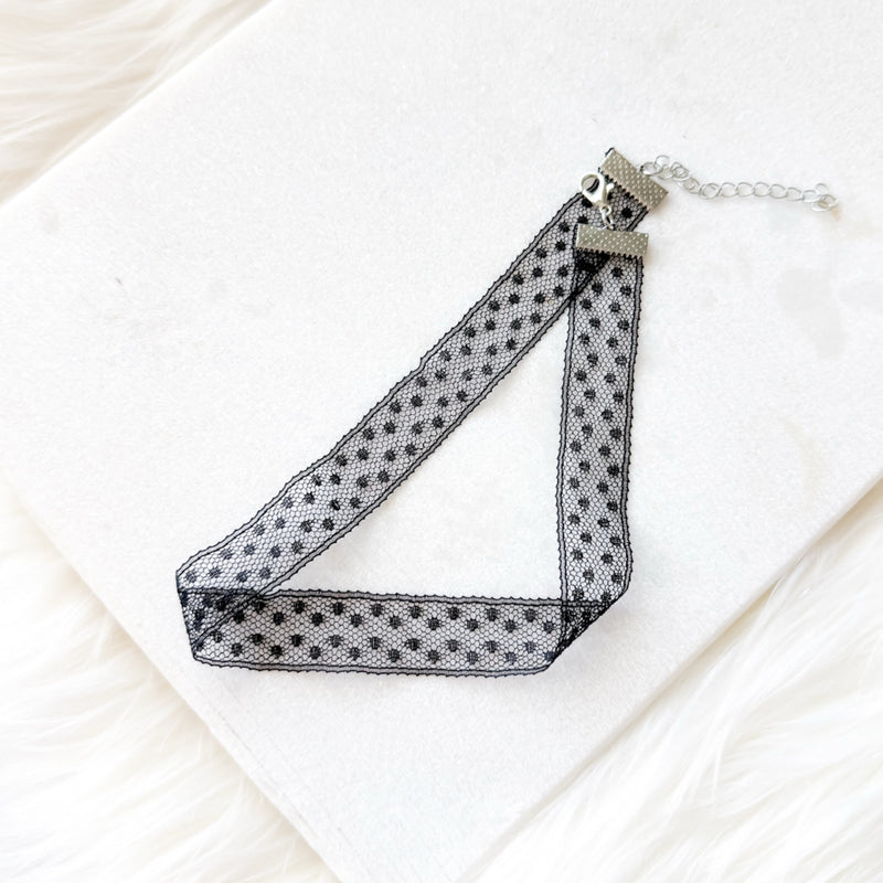 Black polka dot choker necklace on a white background