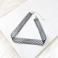 Black and white polka dot choker necklace on a white surface