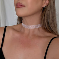 Woman wearing a delicate lace choker necklace against a neutral background