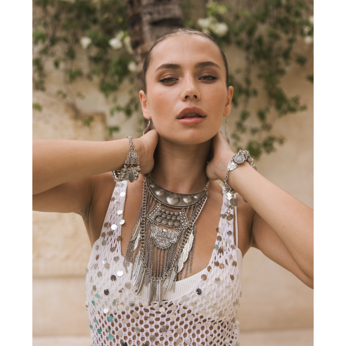 Woman wearing a decorative necklace and earrings with a neutral background  Feathers and Chains Statement Necklace - The Songbird Collection
