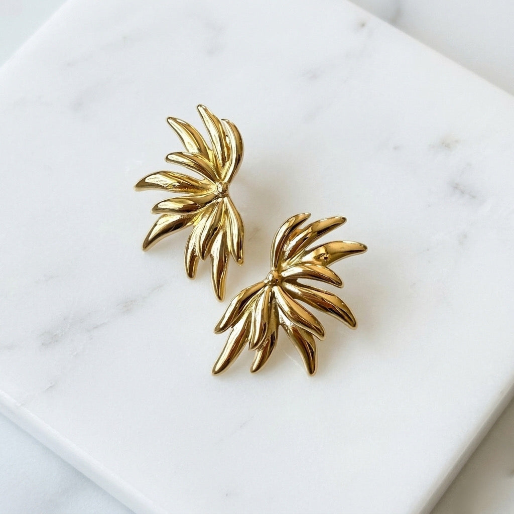 Gold leaf-shaped earrings on a white marble surface - Fireworks Statement Earrings - The Songbird Collection