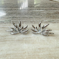 Pair of silver leaf-shaped earrings on a marble surface - Fireworks Statement Earrings - The Songbird Collection