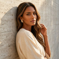 Woman in a beige outfit leaning against a textured wall - Fireworks Statement Earrings - The Songbird Collection