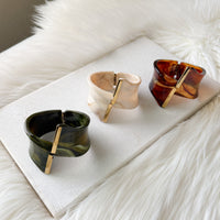 Three tortoiseshell-patterned bracelets on a white surface with a fur background