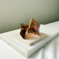 Brown and gold bracelet on a white surface with a neutral background