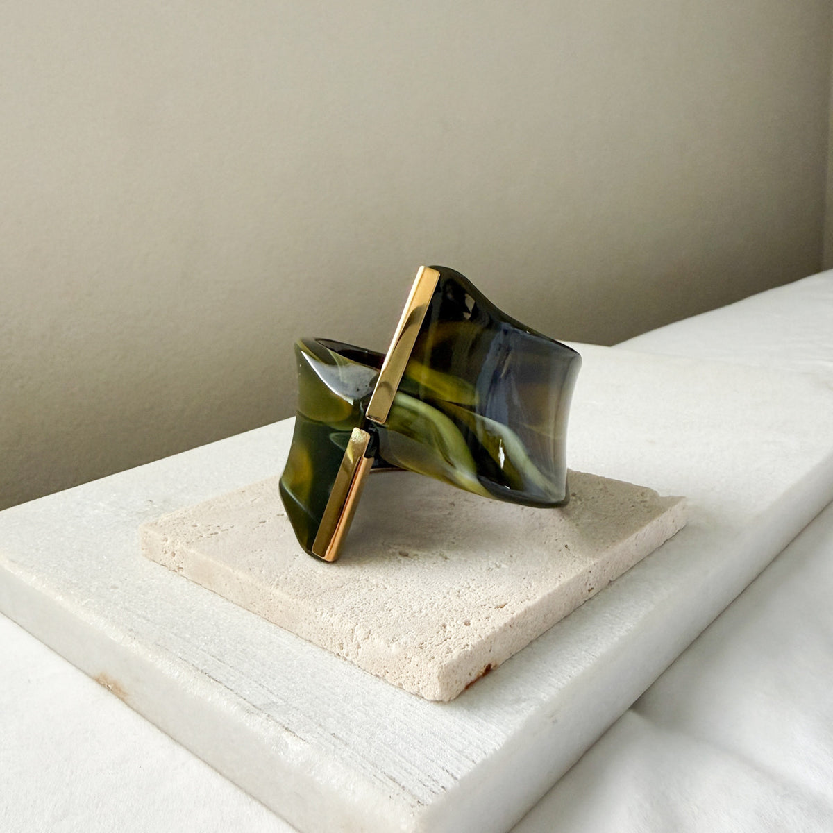 Green and gold bracelet on a white surface with a neutral background